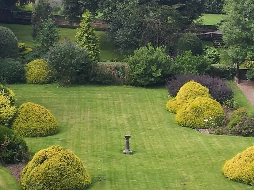 Striped lawn, sundial and clipped shrubs in a well-kept Heswall garden